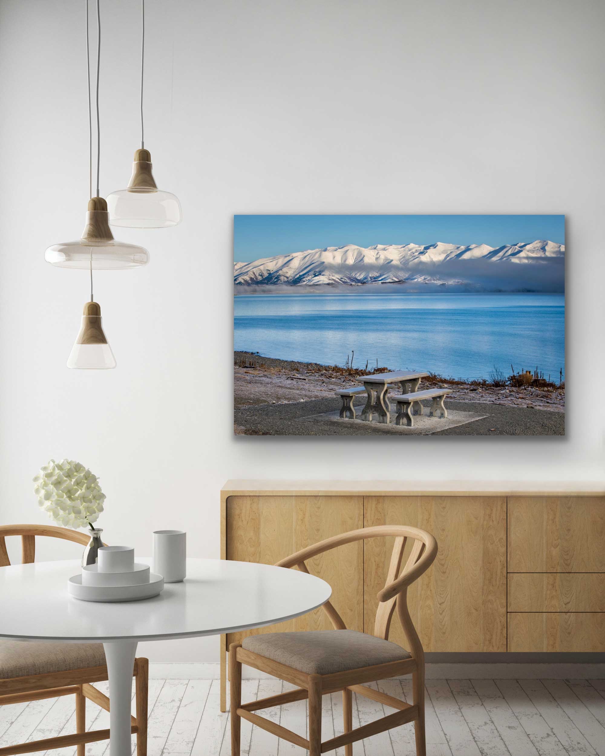 Bright blue Lake Pukaki landscape photograph appearing in situ. See this artwork on the wall above cabinet and table. NZ blue and white interior design art.