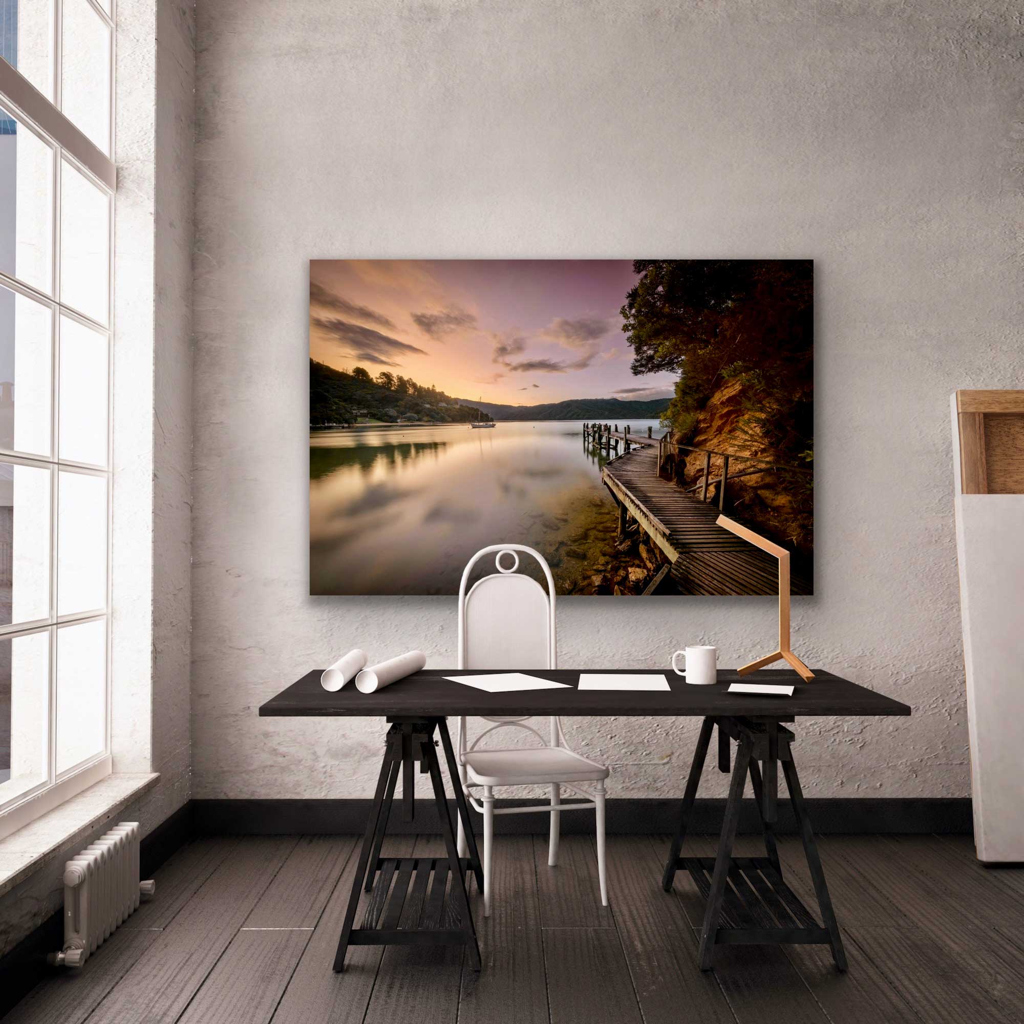 In situ sunset landscape photograph of the boardwalk around Bythell's Bay in Waitaha, Queen Charlotte Sound. Photograph hung on wall behind desk.