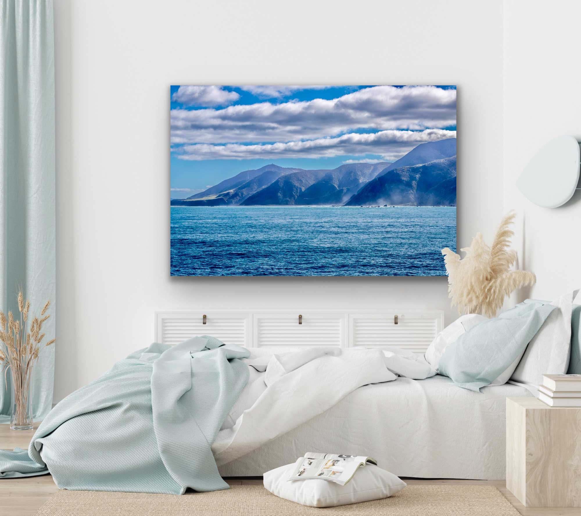 Cook Straight photo in situ. Beautiful landscape photograph of misty fiords along the Cook Strait in New Zealand with low-hanging clouds. Photo hung on wall above a bed.