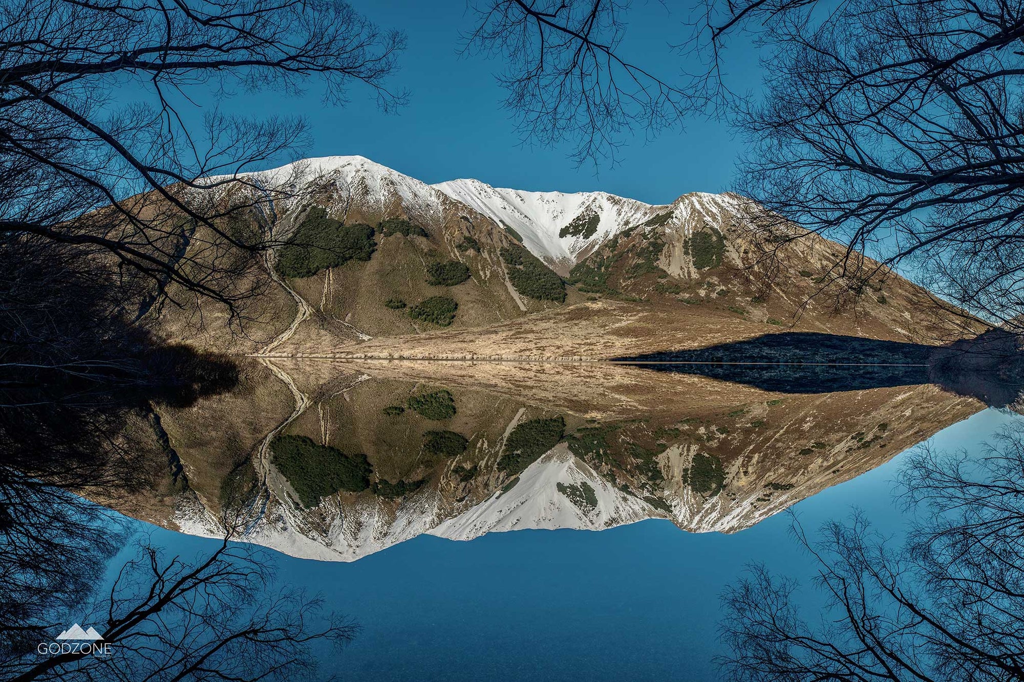 Landscape photograph of reflective Lake Pearson, snowy mountains and trees perfectly reflected in the lake surface. Stunning photographic prints for sale. 