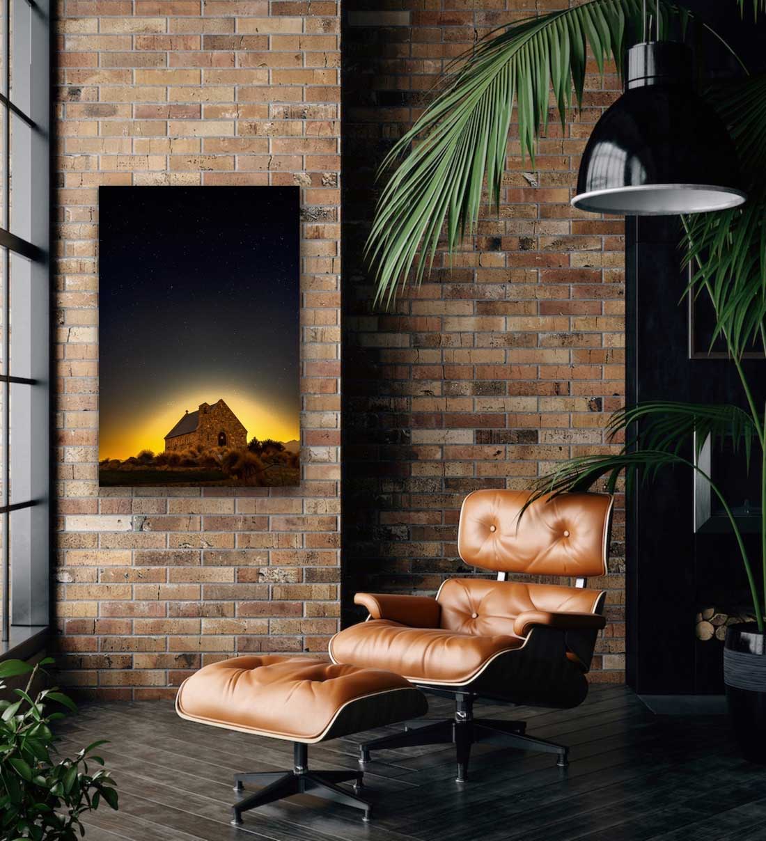 Night photograph of the Tekapo church captured with beautiful moon glow and stars, appearing here in situ. Photograph hung on wall beside easy chair with potted plant.