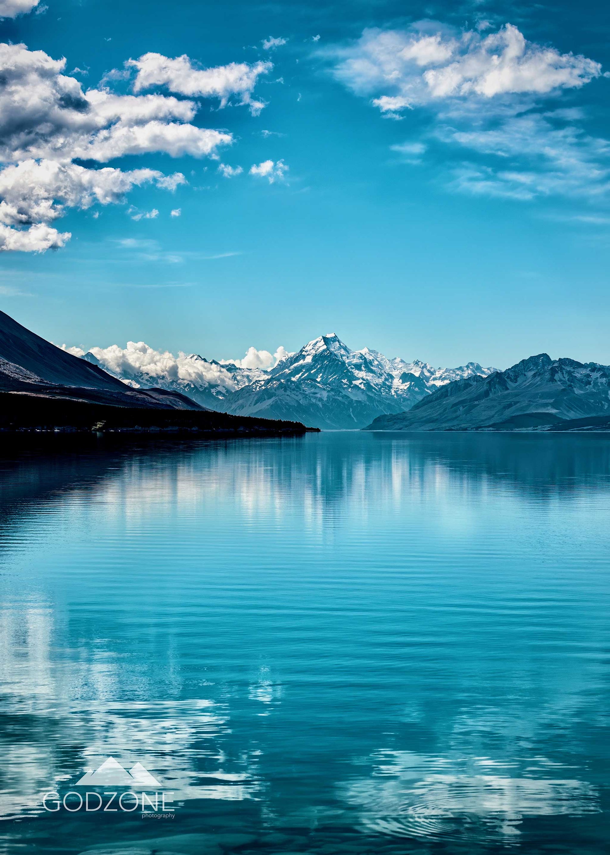 Brilliant landscape photograph of Mount Cook seen across Lake Pukaki. Crisp blue landscape photographs, snowy mountains and glacial lakes. New Zealand affordable art.