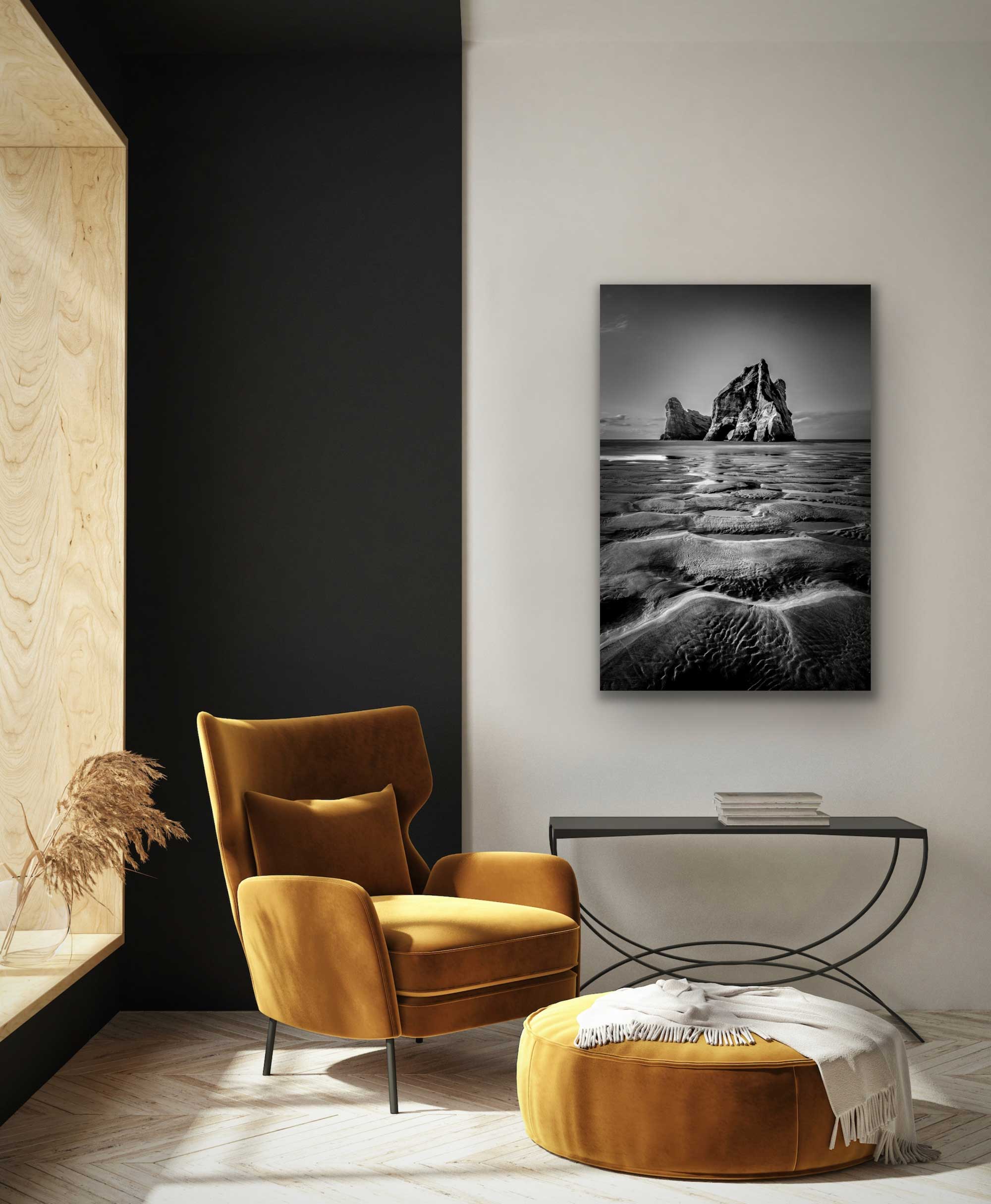 See black and white portrait photograph of archway islands and sandy beach in situ. Photo on wall in alcove with chair and table.