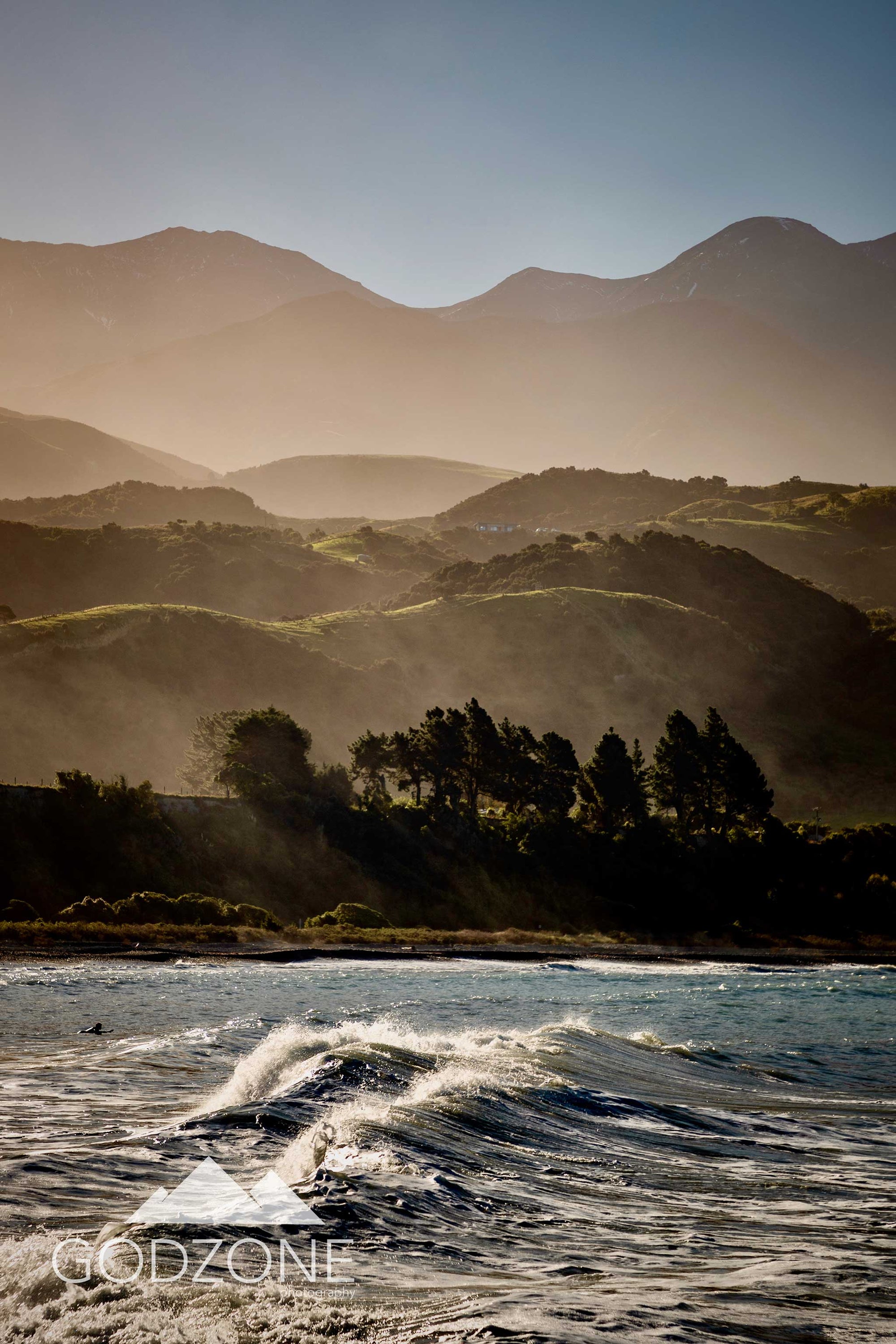 Beautiful photographic print of misty mountains and rolling sea waves at Kaikoura in the South Island of New Zealand. Tall, portrait beach and mountain photography NZ.