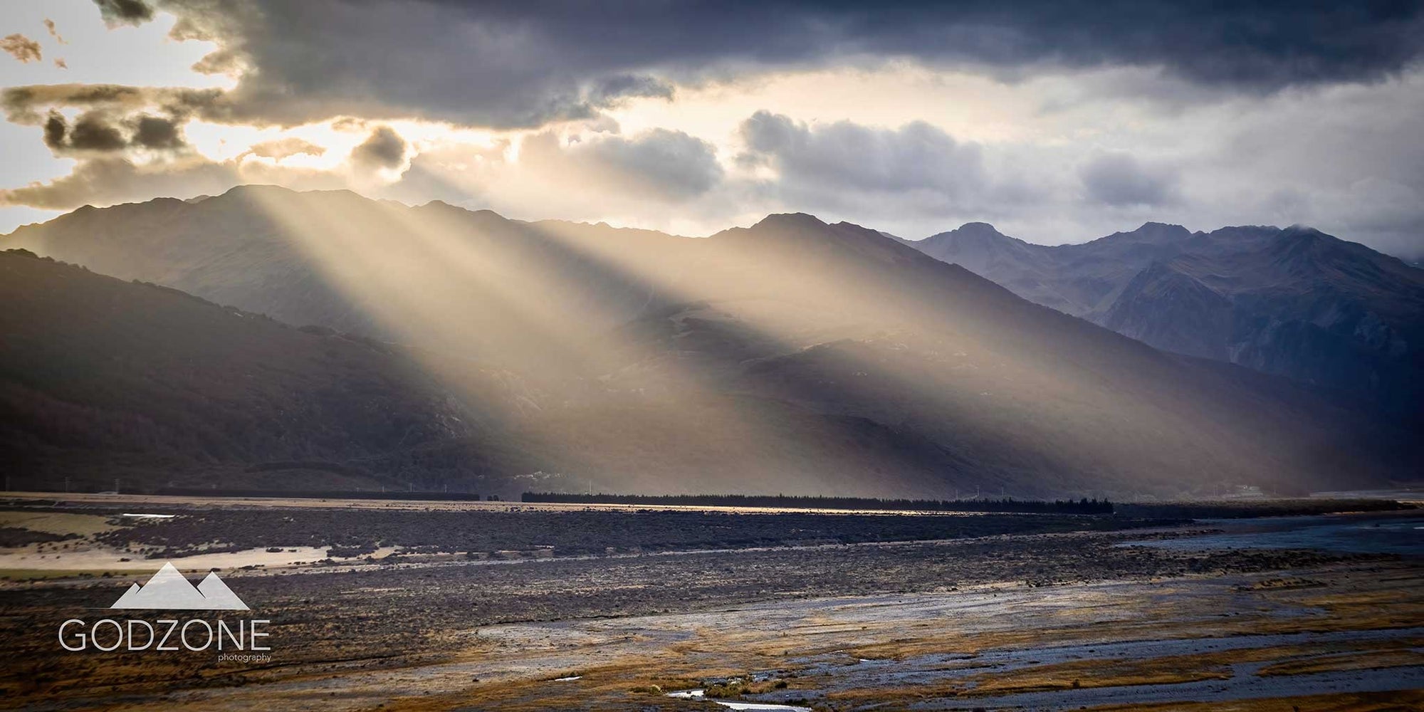 Stunning panoramic landscape photograph of sun rays shining over mountains in Arthur's Pass, South Island New Zealand. 