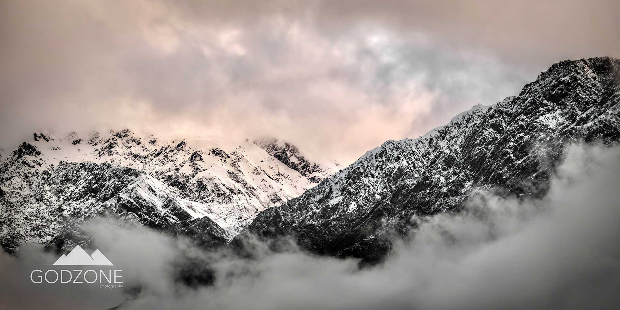 Photographic print of a rugged and snowy mountain line above low clouds. Awesome New Zealand South Island landscape photography. NZ interior design photos. Muted palette.