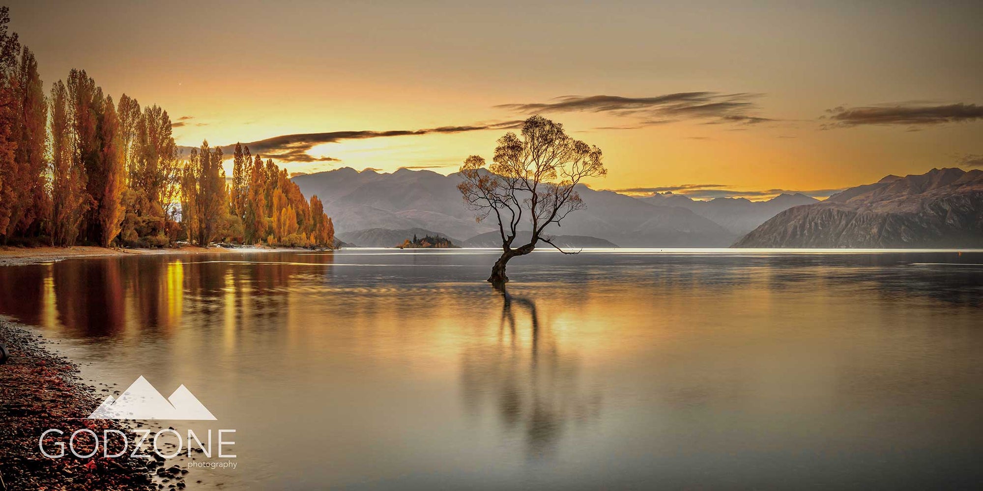 Stunning photograph of the sun setting over the famous tree at Lake Wanaka. New Zealand South Island landscape photography buy now.