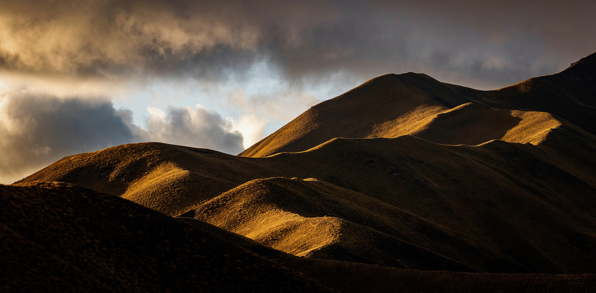 Stunning photograph of rolling golden hills in Lindis Pass, South Island, New Zealand. NZ mountain photography, panoramic.